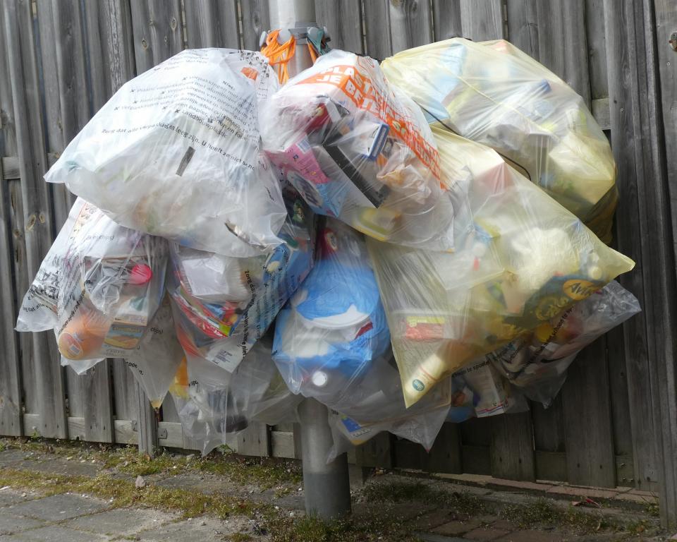 Plastic afvalzakken hangen aan een lantaarnpaal 