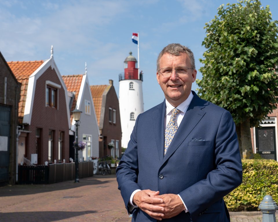 Portret foto van de nieuwe burgemeester van Urk Bart Jaspers Faijer. Op de achtergrond is de welbekende vuurtoren van Urk in beeld