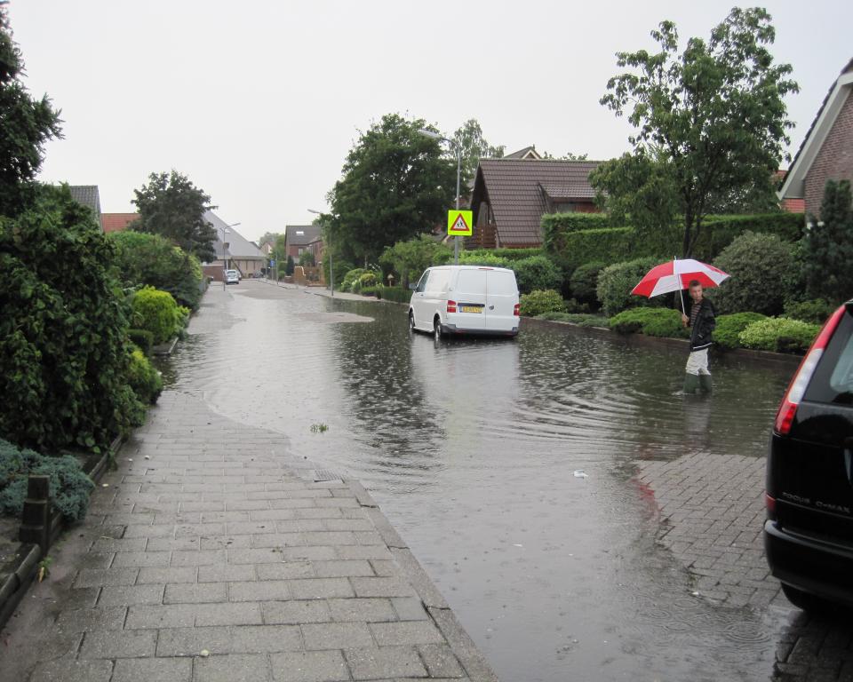 Straat en stoep staan blank na hevige regelval.