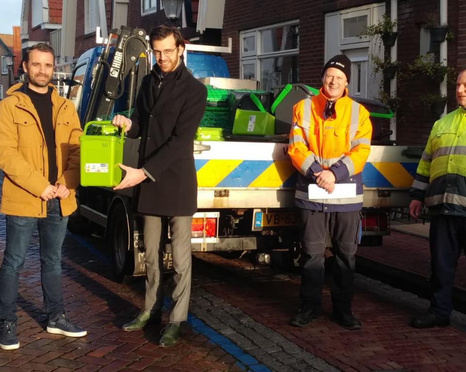 Wethouder Middelkoop reikt de eerste biobak uit aan Hessel van de Berg, bewoner van het oude dorp.