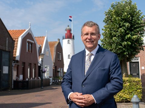Portret foto van de nieuwe burgemeester van Urk Bart Jaspers Faijer. Op de achtergrond is de welbekende vuurtoren van Urk in beeld