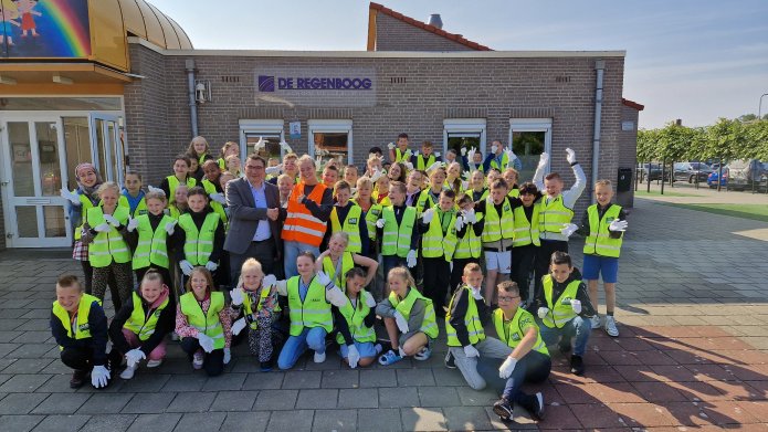 Leerlingen van de Basisschool De Regenboog voor schoolgebouw, samen met Willem Foppen