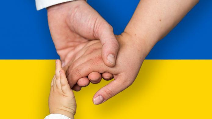 Twee handen en een kinderhandje voor een Oekraïense vlag