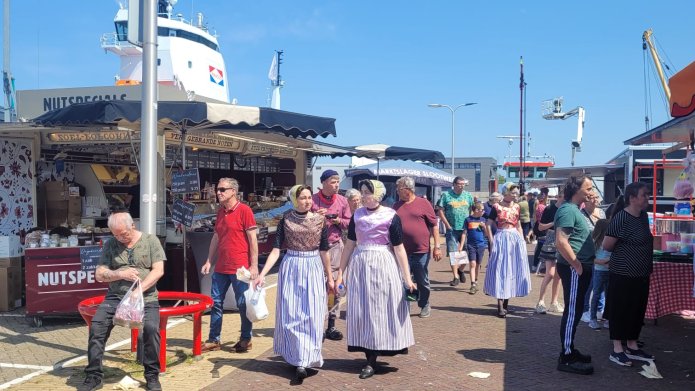 Een foto van de zaterdagmarkt van 2023 in de foto zijn twee kramen te zien met meerdere mensen gekleed in Urker klederdracht 
