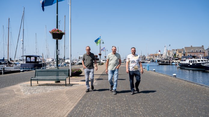 Drie mannen lopen op de haven van Urk