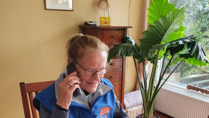 Een oudere mevrouw houdt telefonisch spreekuur voor vragen over het openbaar vervoer