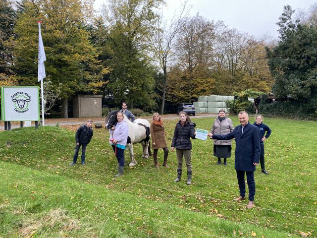 Wethouder Freek Brouwer overhandigt een cheque met een investeringssubsidie aan bewoners van zorgboerderij De Bosrand.