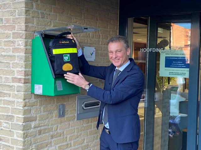 Wethouder Freek Brouwer bij een AED aan de muur van het gemeentehuis van Urk