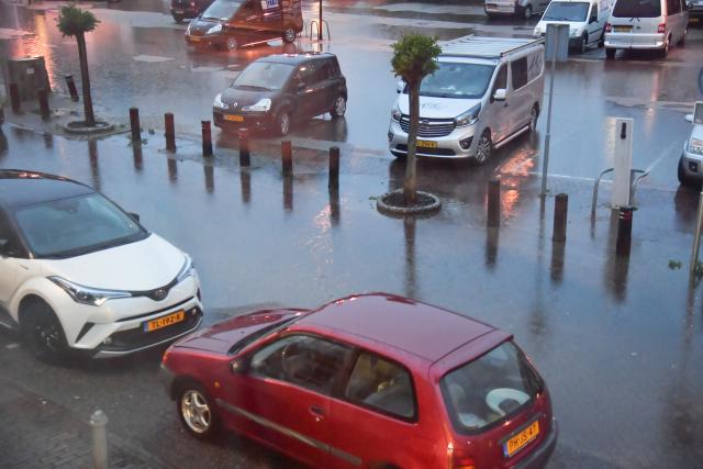 Geparkeerde auto's op het Hofsteeplein staan in het water