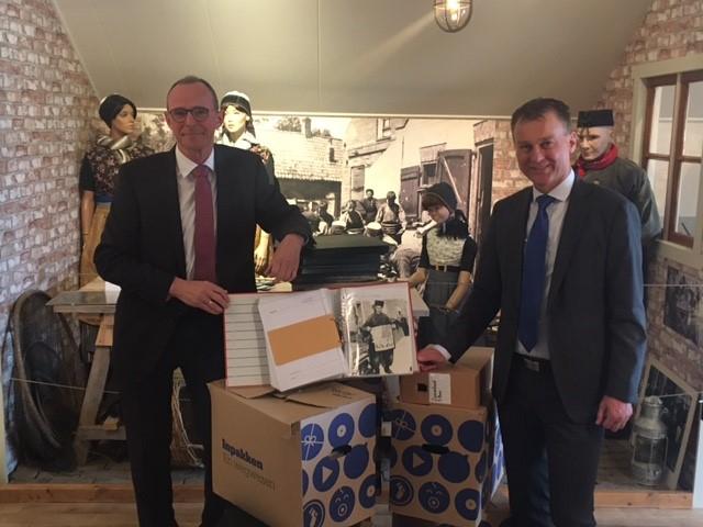 Interim museumcoördinator Jan Verhoeff neemt de fotocollectie van de gemeente Urk in ontvangst na overhandiging van een fotoalbum uit handen van wethouder Freek Brouwer.