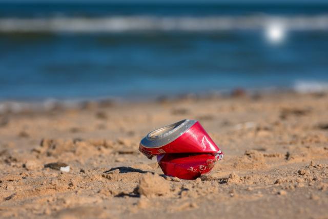 Leeg rood blikje op het strand