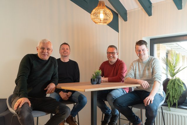 4 mannen zitten aan een tafel