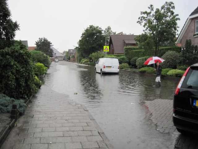 Straat en stoep staan blank na hevige regelval.