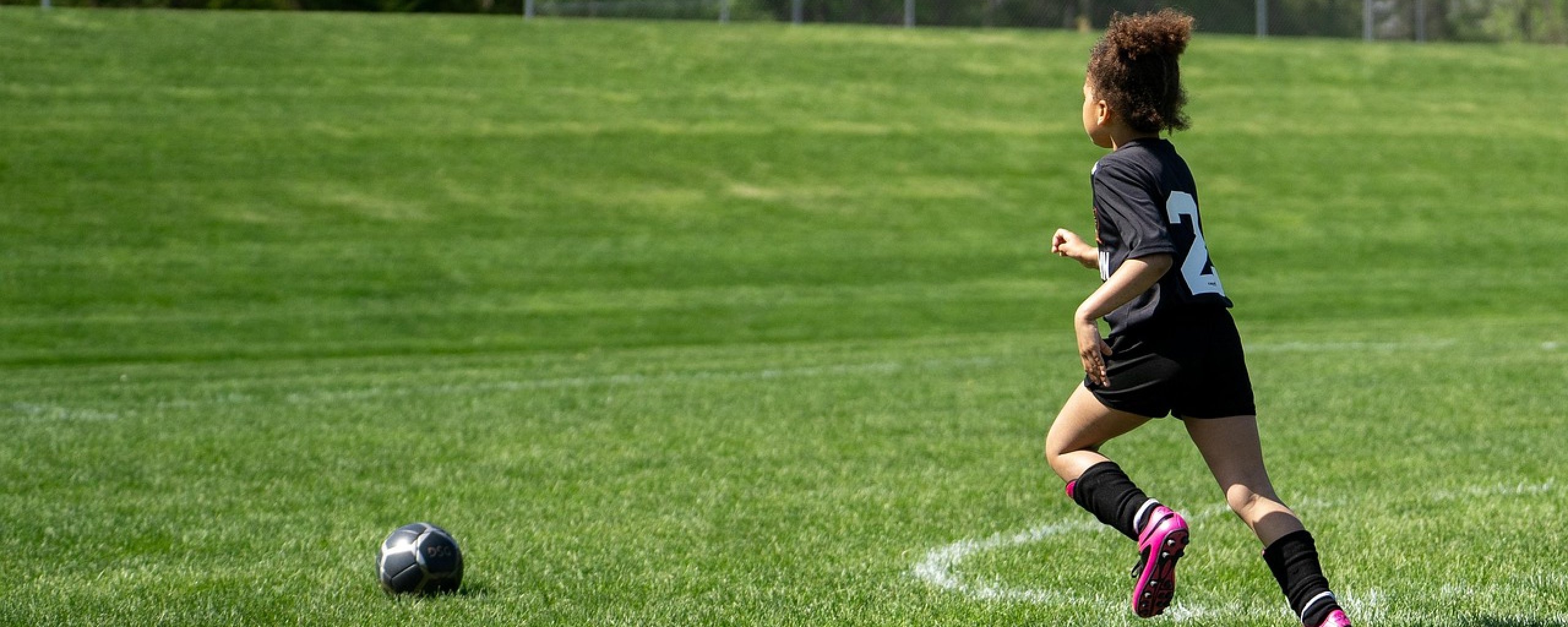 Meisje rent richting voetbal op voetbalveld