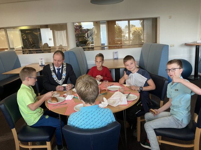 Foto van het ontbijt met de burgemeester een een aantal leerlingen 