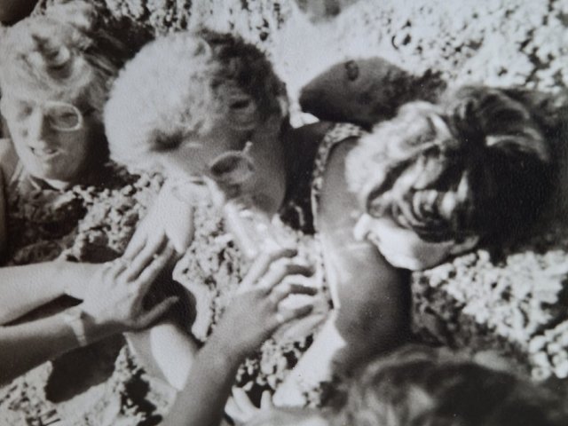 Foto van tante Dinie ingegraven in het zand op een strand