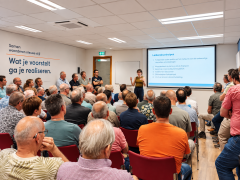 Groep mensen luistert en kijkt naar een presentatie