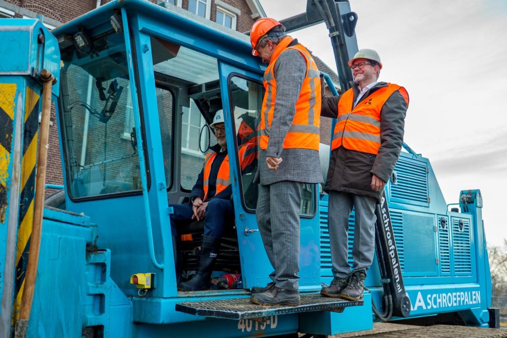 drie mannen in werk kleding bij een bouw kraan