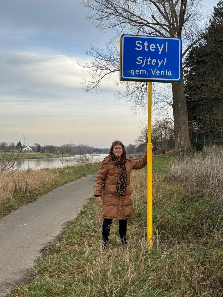 Wethouder Pollux bij het bord van Steyl waar Sjteyl onder staat.