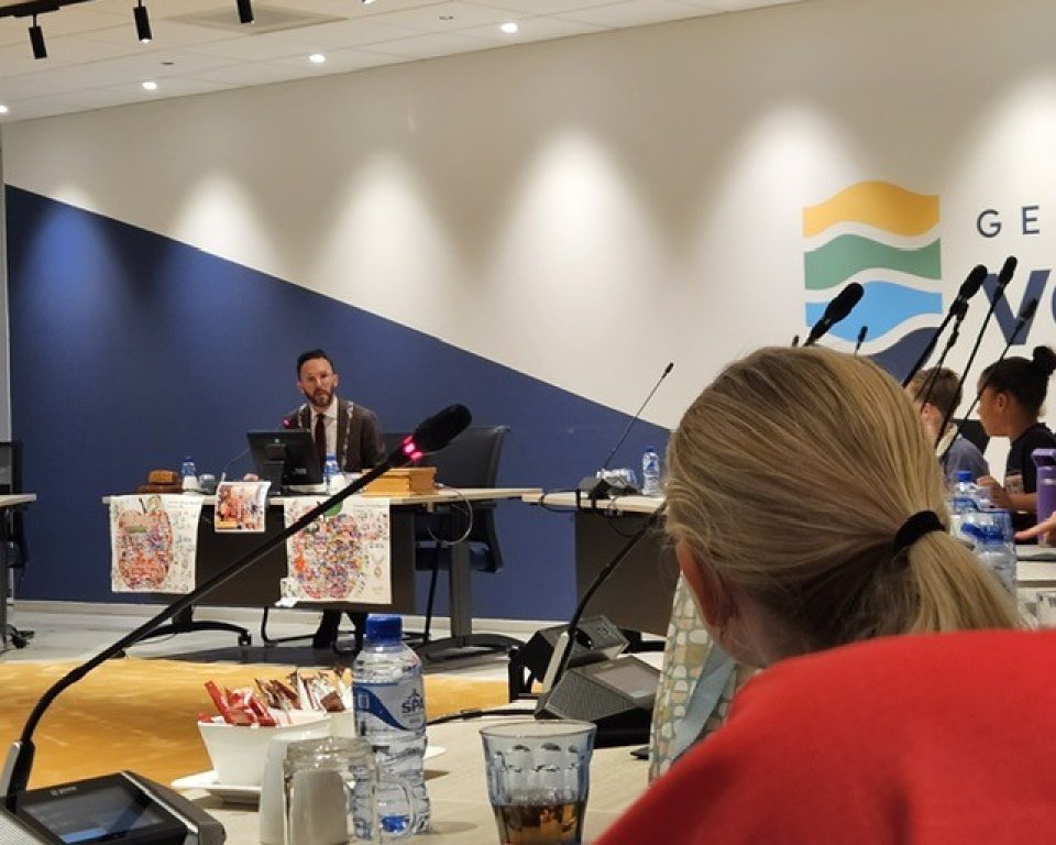 Burgemeester Arno Scheepers in de raadzaal met kinderen aan het ontbijten