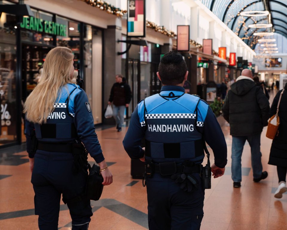 Twee handhavers lopen door het winkelcentrum