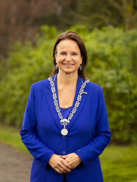 De burgemeester in koningsblauw pak in het park