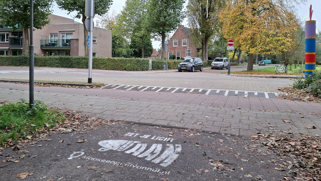 Geschilderde tekst op de weg: 'Zet je licht aan'