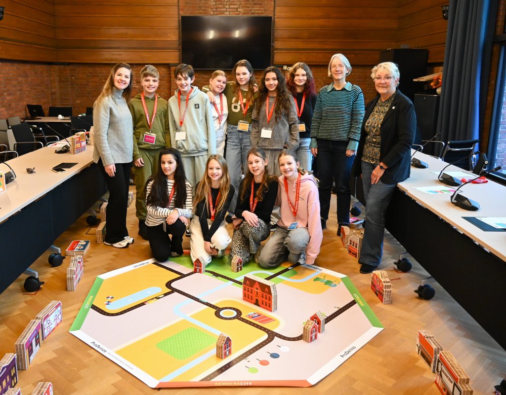 Leerlingen poseren met het spel in de raadzaal