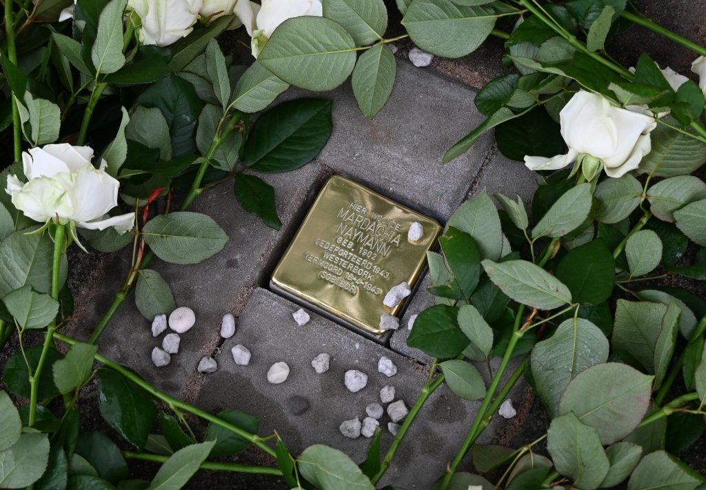 De Stolperstein met bloemen en steentjes