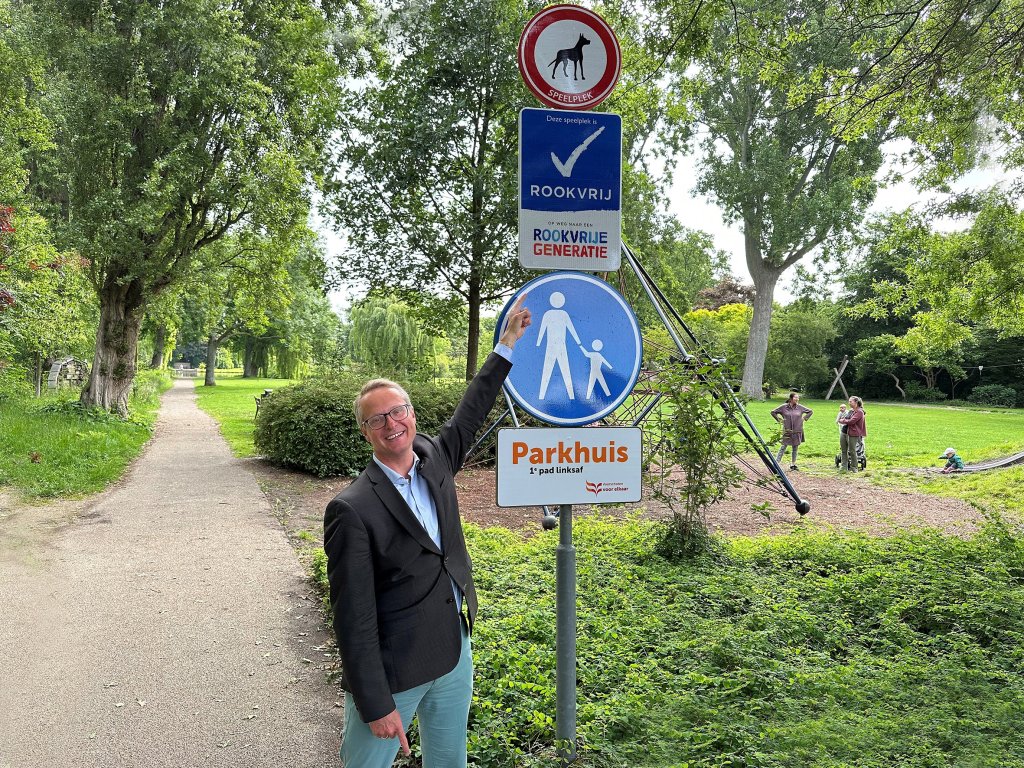 De wethouder wijst naar het bord in het park