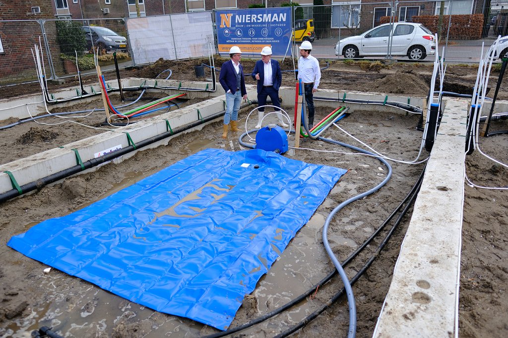 De wethouder bekijkt een waterzak op de bouwplaats