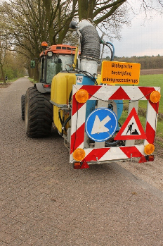 Foto van tractor met aanhanger waar de tank met biologisch bestrijdingsmiddel staat opgesteld.