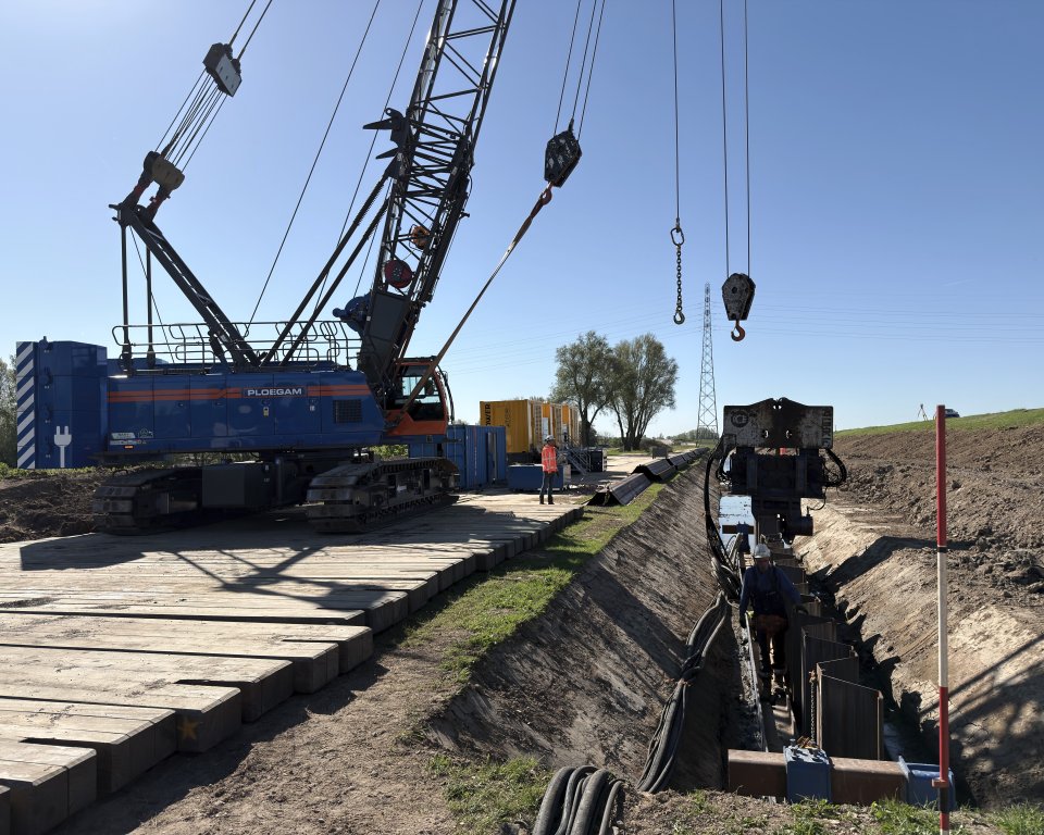 Elektrische kraan werkt aan dijkversterking.