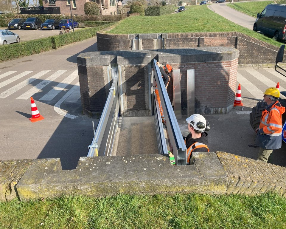 Aluminium balken worden op elkaar gestapeld in een doorgang in de dijk