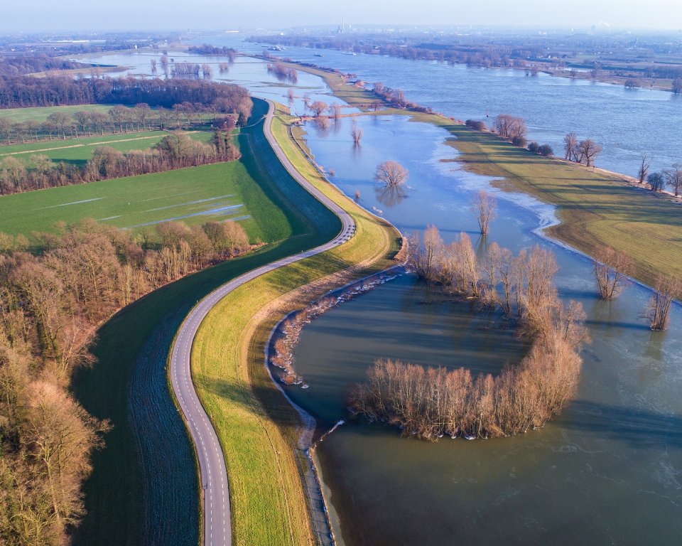 Foto van een dijk aan de Waal tijdens hoogwater. 