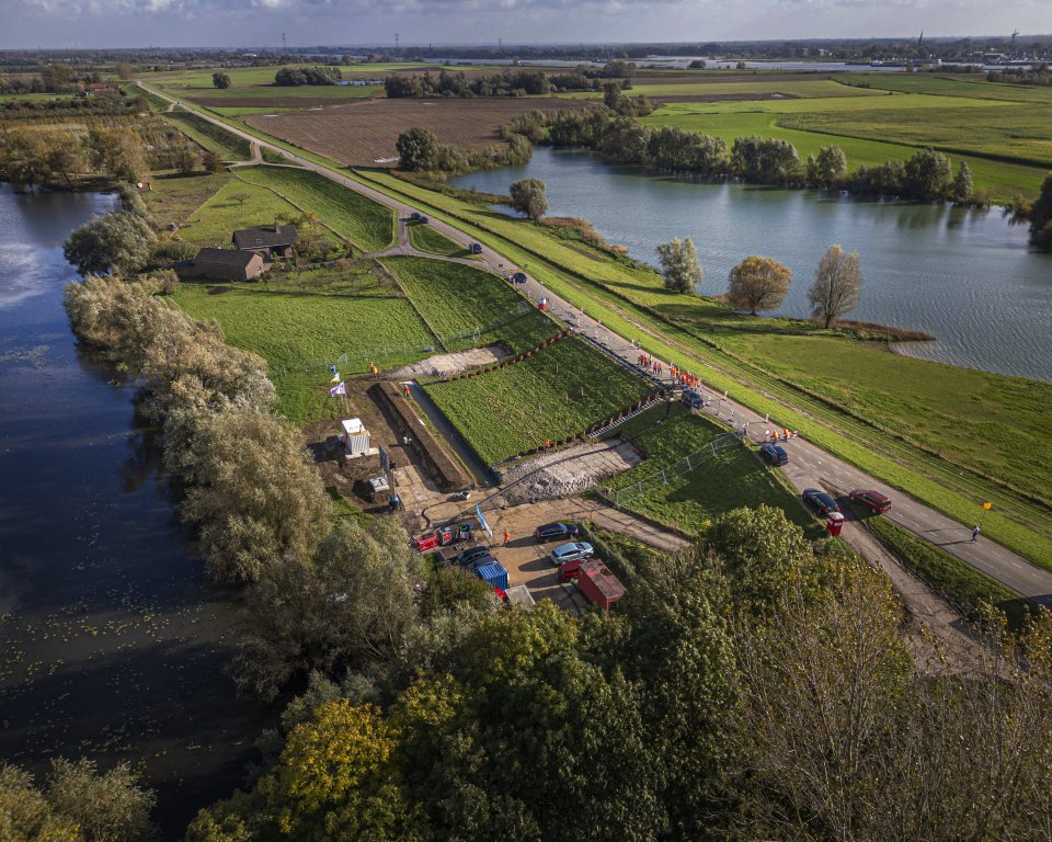 Waterschappers en onderzoekers van Deltares kijken hoe de veldproef aan de Waal bij Ochten verloopt.