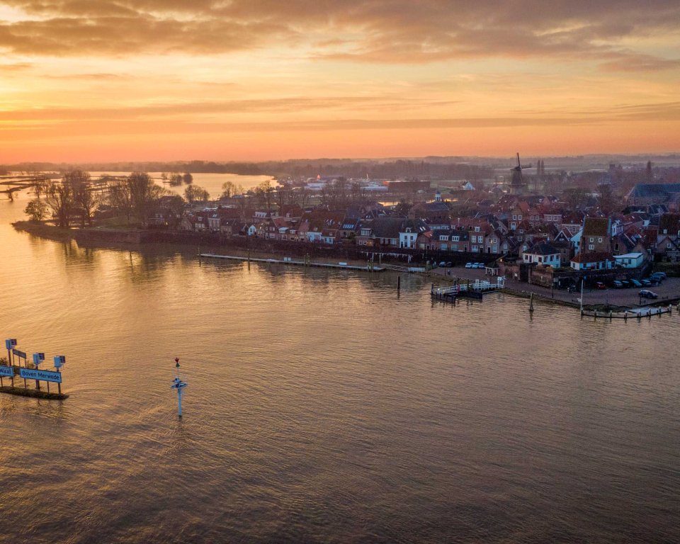 Beeld van boven van Woudrichem met ondergaande zon met hoogwater
