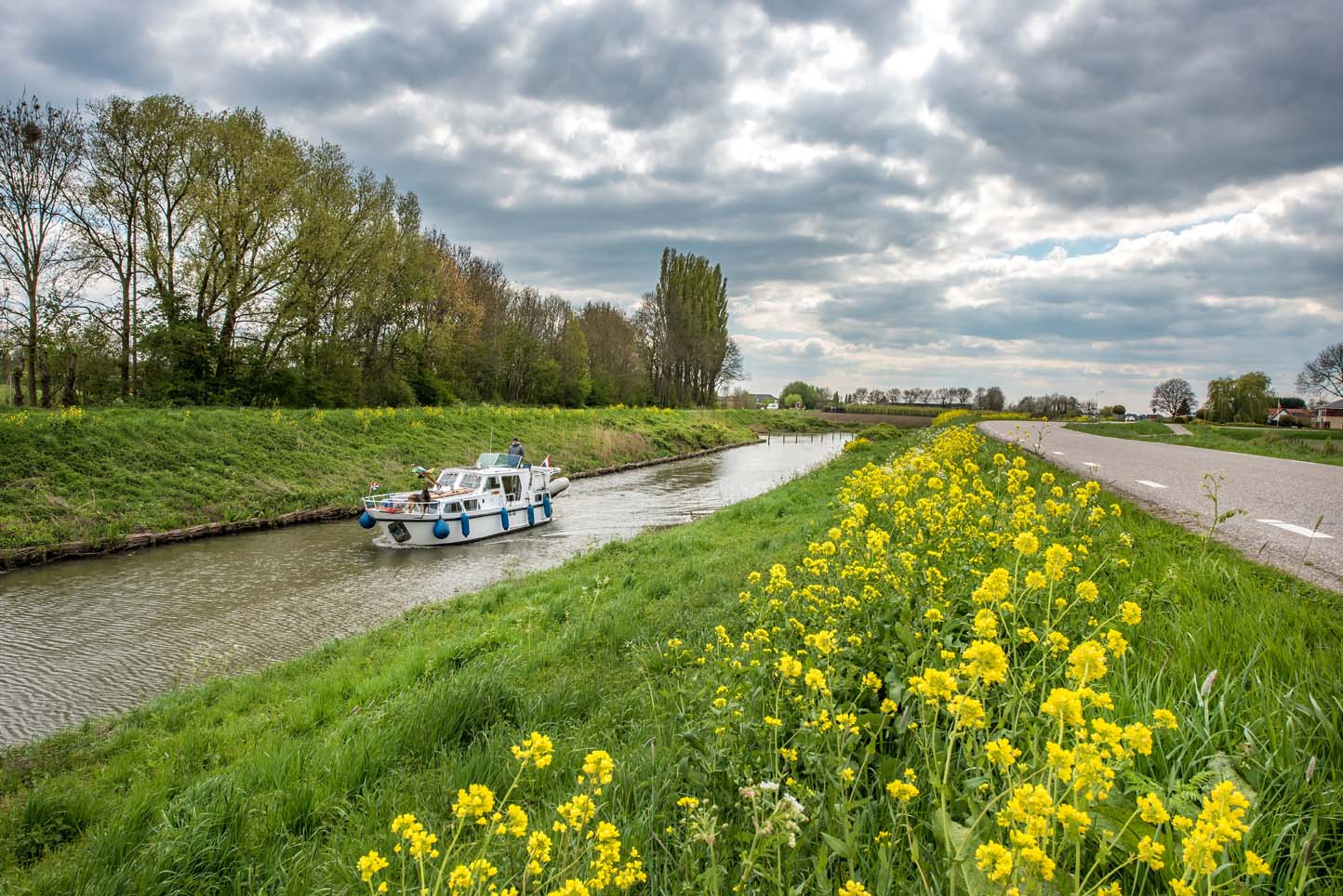 Een bootje op het water met een dijkje en weg