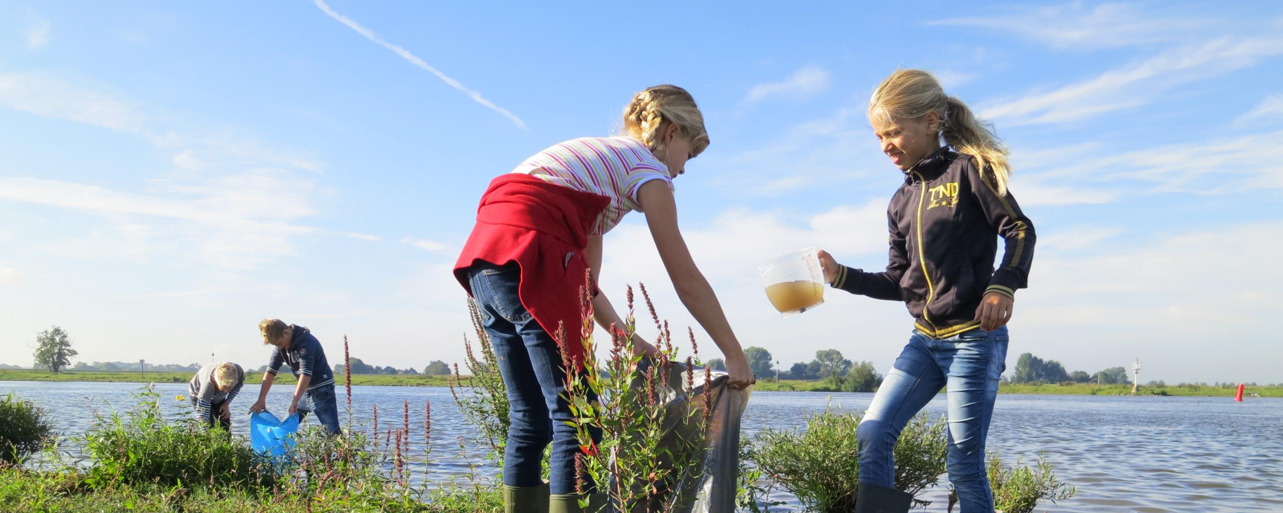 Kinderen doen waterproefjes langs de rivier