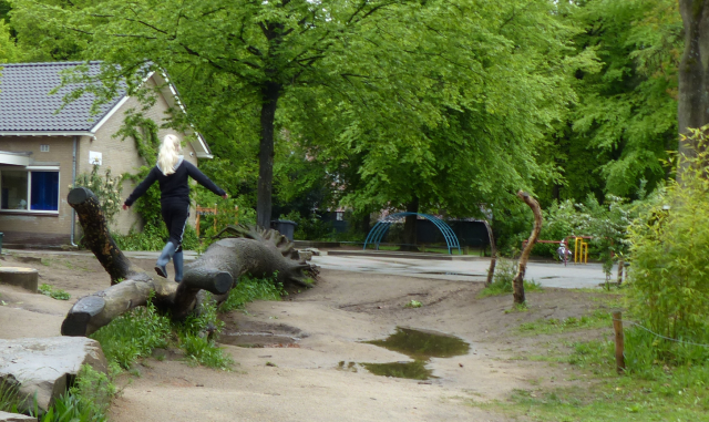 Leerling schoolplein balanceert op boomstam op klimaatactief schoolplein obs Slingerbos