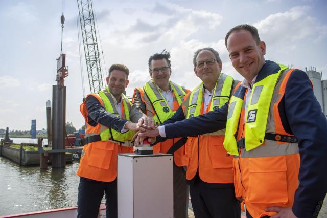 Erik Wagener (HWBP), Hans Wijnen en Peter Staats (WDODelta) en Rick Lormans (namens Dijkzone Alliantie Zwolle) geven met een druk op de knop opdracht voor het slaan van de eerste, 12 meter lange, damwandplank bij de Strekdam van de Scania Haven in Zwolle. Achter de damwand staat een deel van het gedicht van stadsdichter Bauke Vermaas.