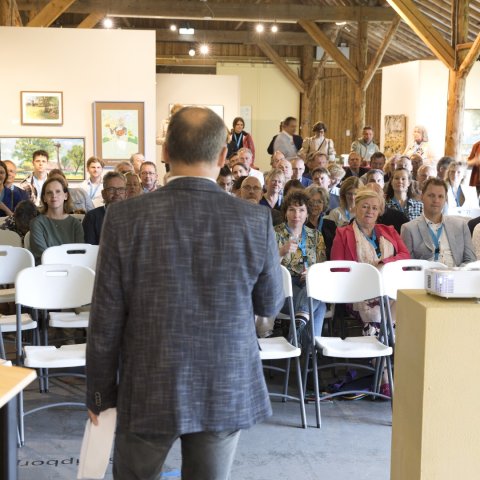 Wethouder Bert Nederveen voor de groep in het Rijtuigenmuseum