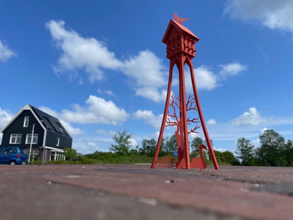 Miniatuurversie van de rode duiventil op vier poten met daartussen een grafische weergave van een boom en zwaan
