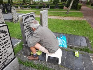 Vrijwilliger werkt historisch graf bij