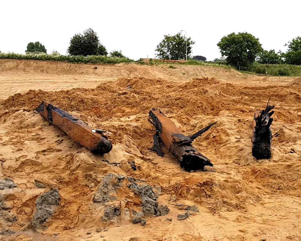 De langste paal is met forse kracht door een machine uit de oude rivierbedding van de Maas getrokken, waarbij de paal in stukken is gebroken. Het onderste deel zit nog in de bodem.