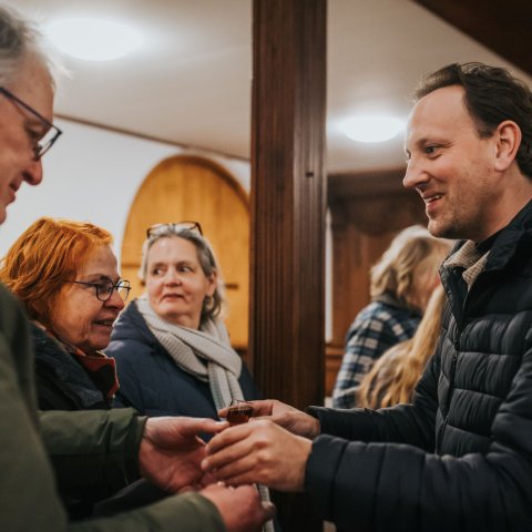 Wethouder Roelof Theun Hoe geeft inwoner een drankje tijdens herdenking