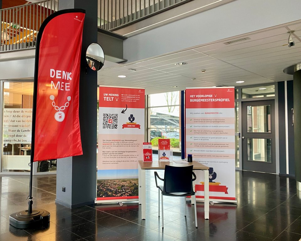 tafel met stoel en banners met uitleg over deelname en een beachflag