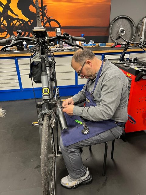 Hisham Kasem staat in de werkplaats van Weerman Fietsen in Wolvega en is geconcentreerd bezig met een fietsreparatie