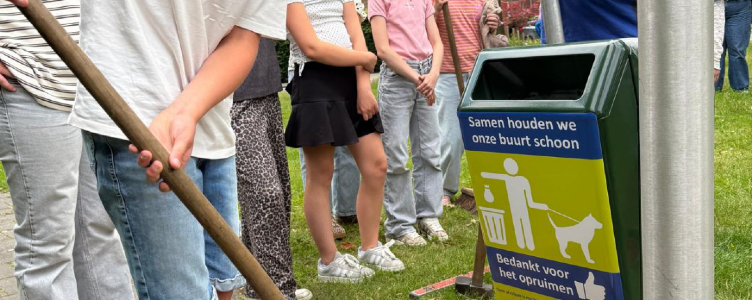 Lid van de Kinderraad schept zand bij de plaatsing van een nieuwe prullenbak in de speeltuin in Enter.