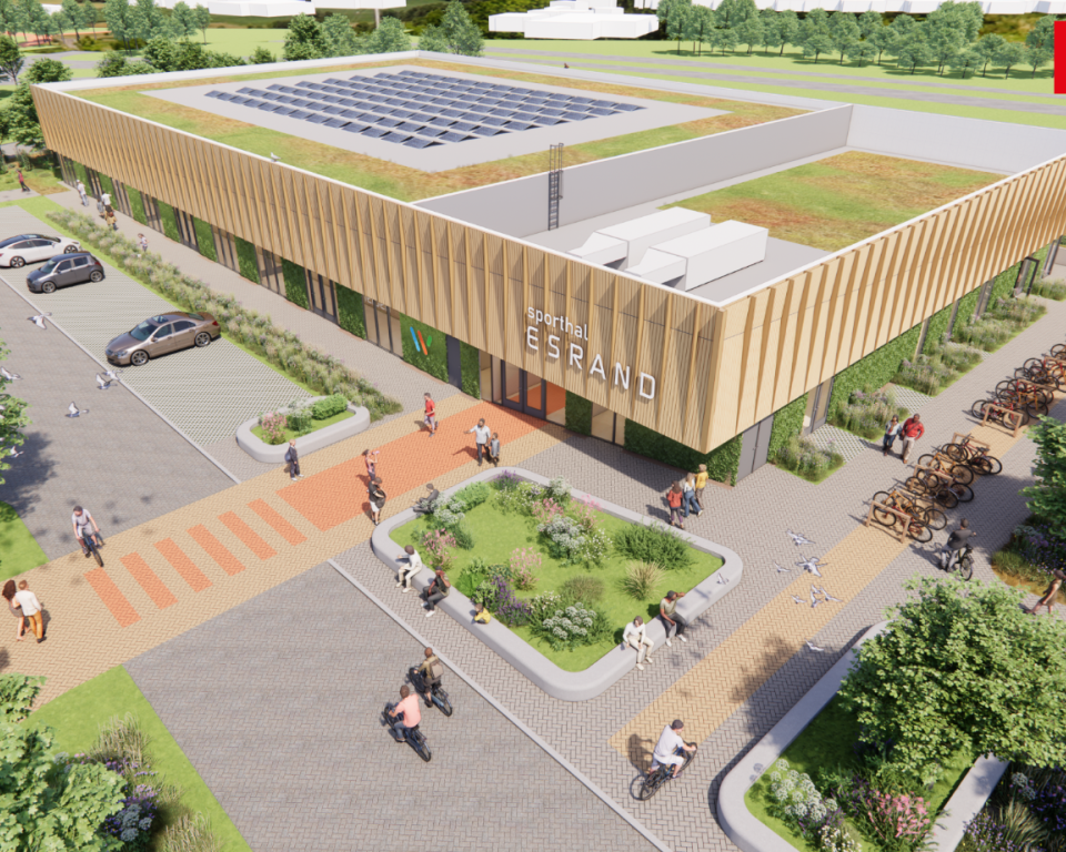 Buitenaanzicht van de nieuwe sporthal Esrand met een houten gevel, groene daken met zonnepanelen, parkeerplaatsen en fietsenstallingen.